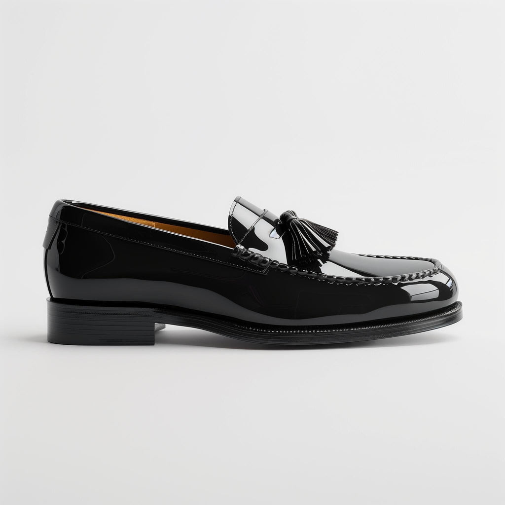 Black patent leather tassel loafer shoe with a stacked heel and visible stitching on a white background.